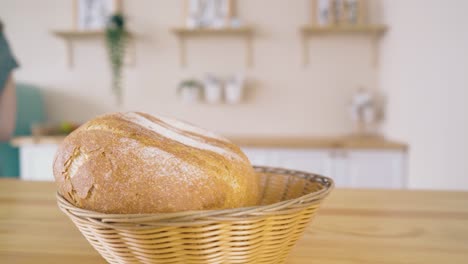 loaves of tasty bread and girl taking rye bun at table