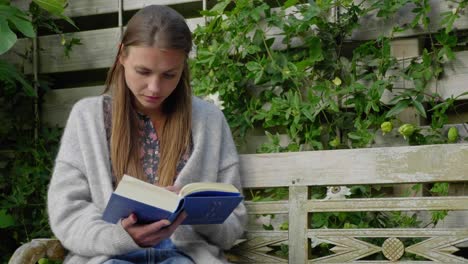 mujer joven lee un libro en un banco en el jardín, medio