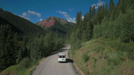 Antena-Dron-Cinemática-Hielo-Lago-Cuenca-Inicio-Del-Sendero-Conduciendo-Furgoneta-Carretera-Del-Condado-Verano-Temprano-En-La-Mañana-Silverton-Telluride-Colorado-Montañas-Rocosas-Bosque-De-álamo-Temblón-14er-Picos-Adelante-Seguir-Movimiento