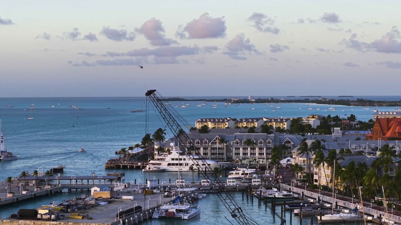 Dron siguiendo un helicóptero volando sobre la costa de Key West, atardecer en EE. UU.