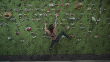 mujer escalando roca en la pared de escalada interior