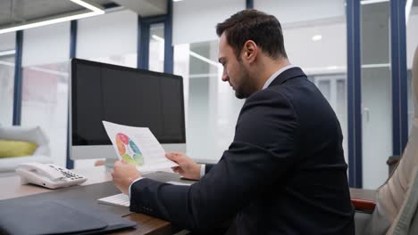 businessman reviewing a financial report and analyzing charts for strategic insights at office desk