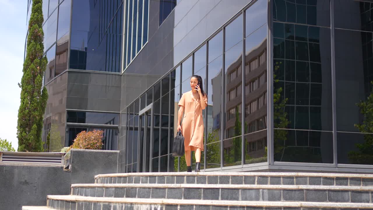 Businesswoman walking down stairs while talking on mobile phone