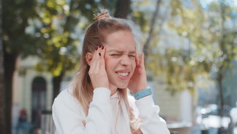 mujer disgustada frotando las sienes para curar el problema del dolor de cabeza sufriendo de estrés por migraña en la calle