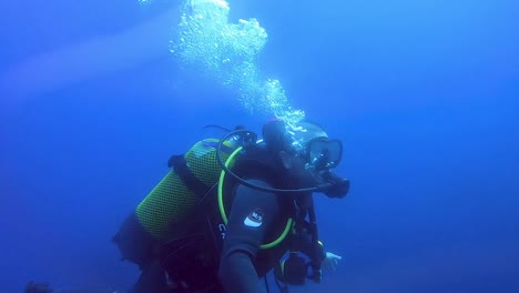 diver swims underwater in the blue bay of fornells in menorca, spain. medium shot