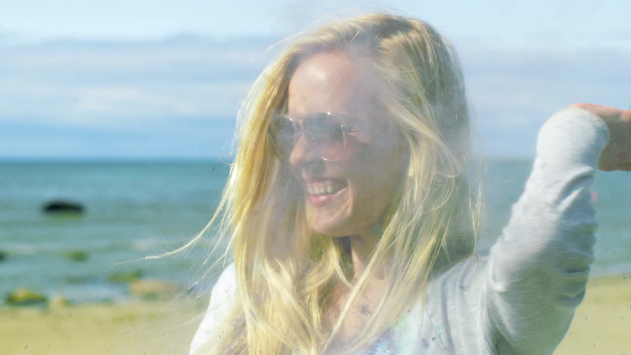Two Beautiful Happy Girls Celebrate Holi Festival By Throwing Colorful Powder in the Air and Laughing. They're By the Sea and Have Lots of Fun.