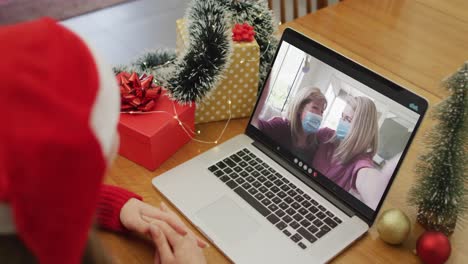 Glückliche-Kaukasische-Frau-Bei-Einem-Videoanruf-Mit-Freundinnen-In-Gesichtsmasken-Zur-Weihnachtszeit