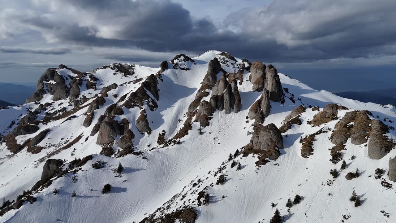 montañas de ciucas cubiertas de nieve bajo un cielo nublado, dramáticos picos escarpados, vista aérea