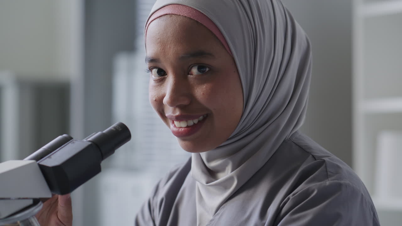 Portrait of Smiling Female Scientist in Hijab near Microscope in Lab