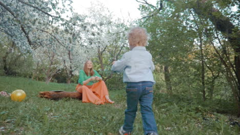 Mother-and-little-son-having-happy-time-in-bloomy-garden