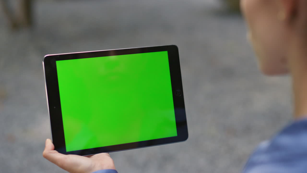 mano usando la tableta verde al aire libre primer plano. la niña deslizando el dedo chroma teclado