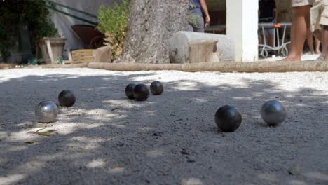 people at the beach playing a game of petanque in the sunshine