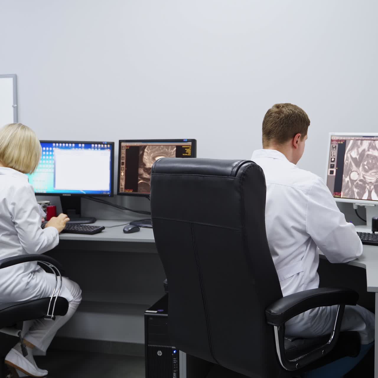 Laboratory room for magnetic resonance imaging analysis. Male and female colleagues sit at computers checking the scans