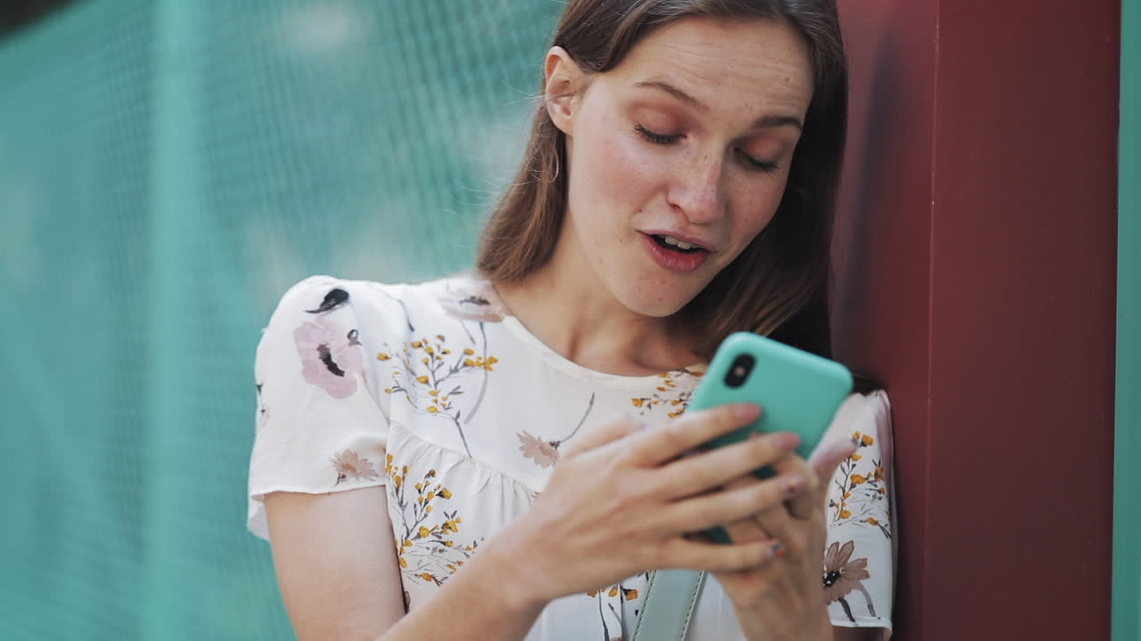Giovane donna che reagisce con sorpresa e gioia mentre usa lo smartphone