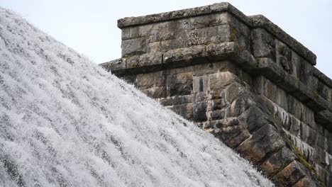 Closeup-of-the-top-of-a-reservoir-dam-weir-with-water-cascading-over-the-top-like-a-waterfall-at-Fernworthy-in-Devon,-England