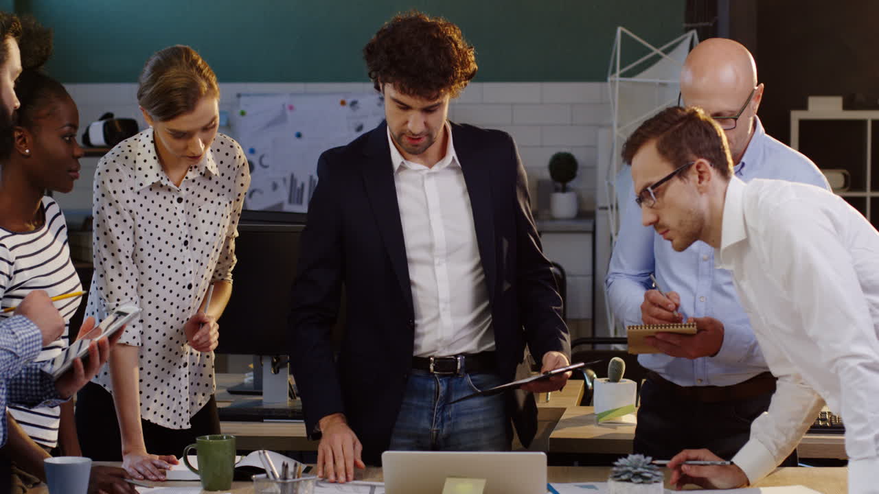 многонациональная бизнес-команда, анализирующая документы, диаграммы, финансовые отчеты и графики в офисе