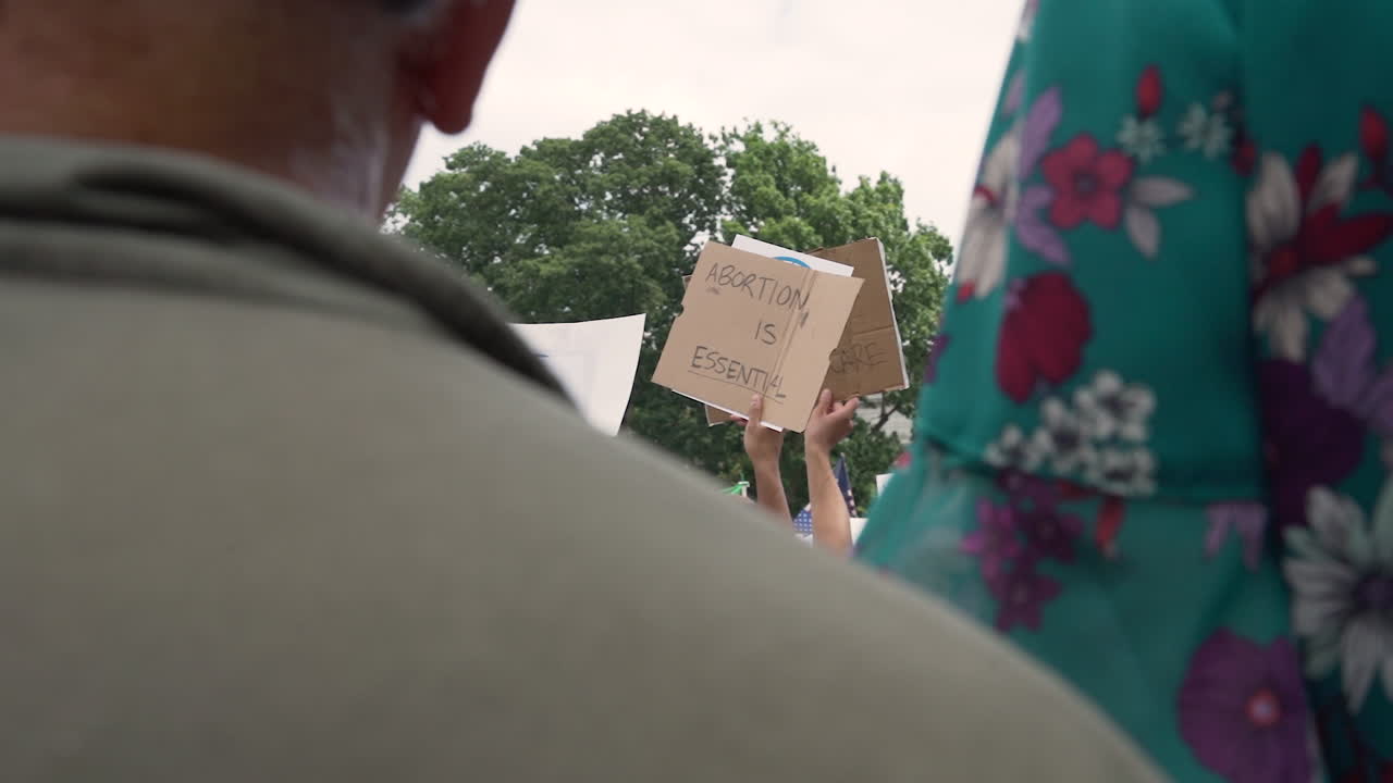 사람들의 군중 속에서 낙태 법적 표지판을 지키십시오.