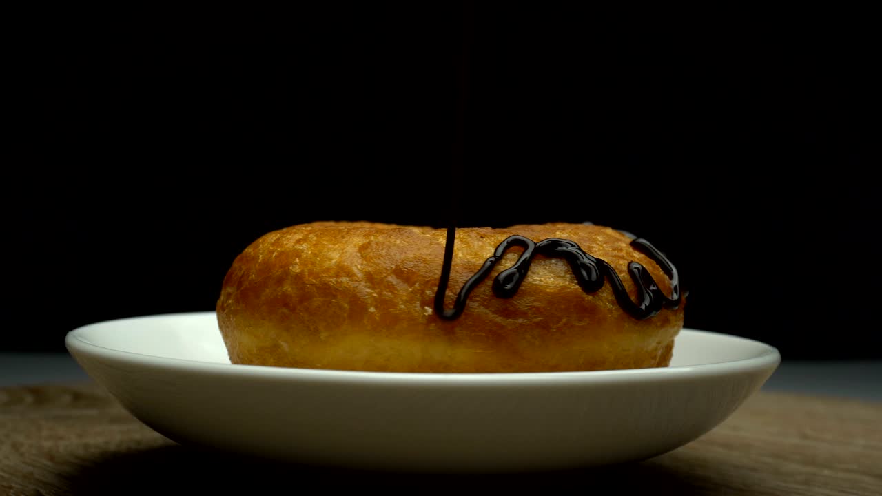 deliciosa rosquilla dulce girando en un plato. vertiendo con chocolate caliente.