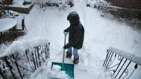 A man clears the snow on the stairs to a house with a shovel