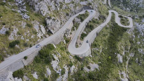 Vista-Aérea-De-Drones-De-Un-Coche-Bajando-Rincones-Ventosos-De-Una-Carretera-De-Montaña-En-Sa-Calobra,-Mallorca,-España