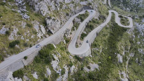 vista aérea de drones de un coche bajando rincones ventosos de una carretera de montaña en sa calobra, mallorca, españa