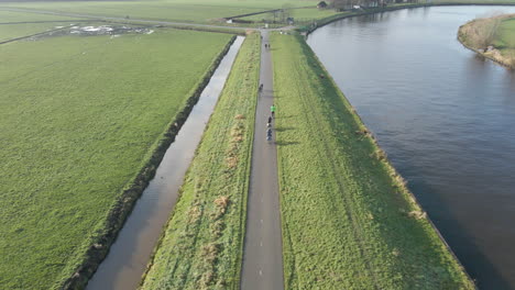 drone following bicyclists cycling over dike