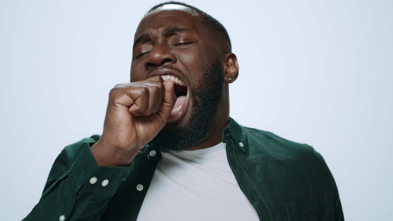 Portrait of tired african handsome man posing on grey background in studio.