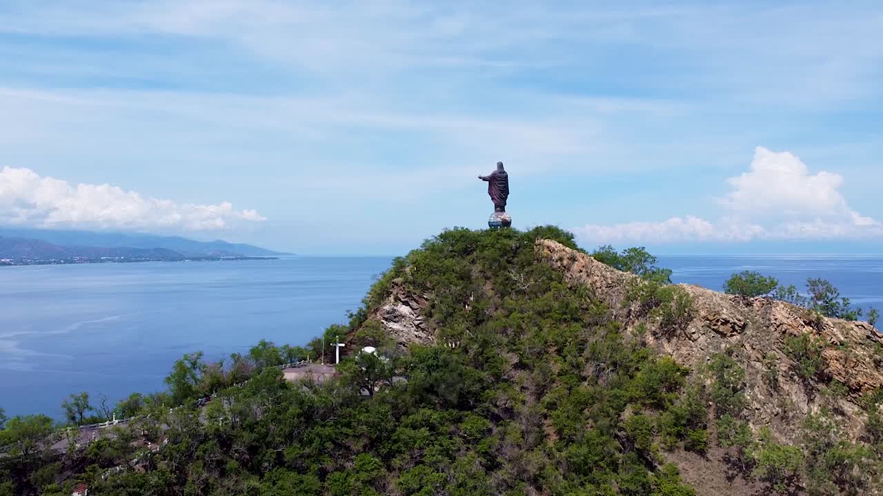Aerial drone view lowering over Cristo Rei statue and ocean in capital city Dili, Timor-Leste, Southeast Asia