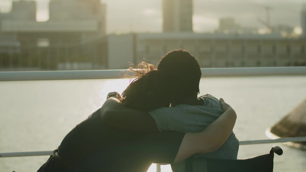 Coppia felice con disabilità che guarda il tramonto e si abbraccia