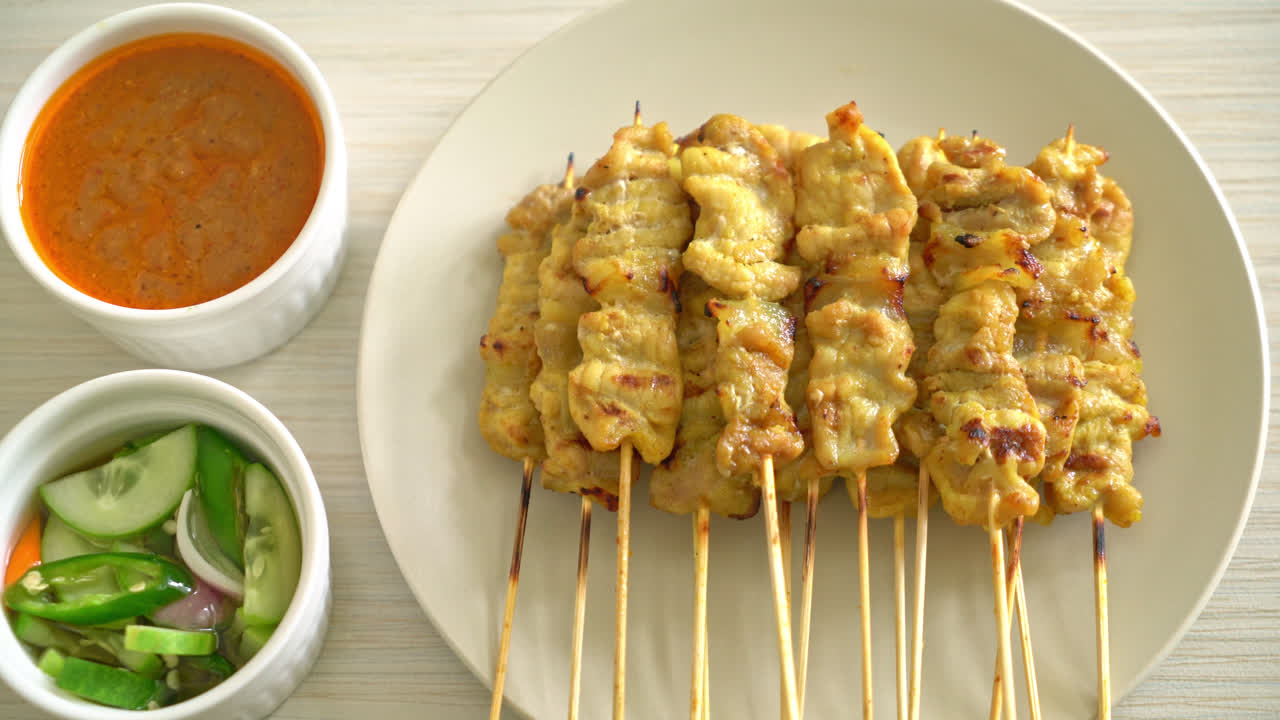 Possuvarras satay-kastikkeella sekä suolakurkuilla, jotka ovat viipaleiksi leikattuja kurkkuja ja sipuleita viinietikassa – aasialainen ruokatyyli