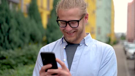 Retrato-De-Un-Hombre-Usando-Su-Teléfono-Inteligente-Y-Sonriendo-Al-Aire-Libre