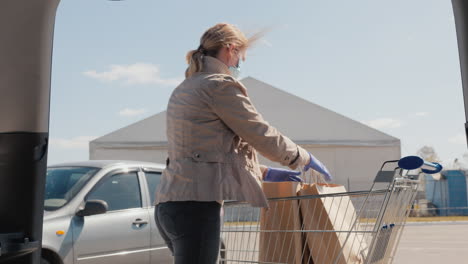 Shopping-During-The-Epidemic---A-Woman-Puts-Bags-Of-Food-In-The-Trunk-Of-A-Car-1