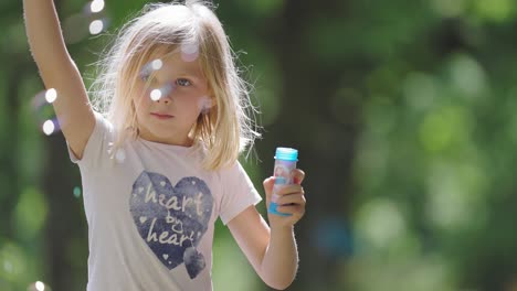 A-blonde-fair-skinned-girl-plays-outside-blowing-soap-bubbles