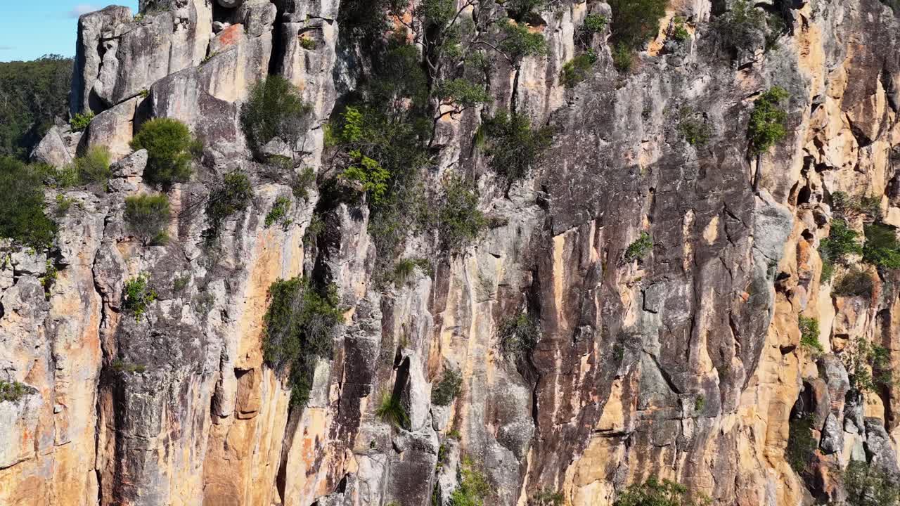Aerial view of Nimbin's rugged cliffs, showcasing natural rock formations and lush greenery under bright sunlight