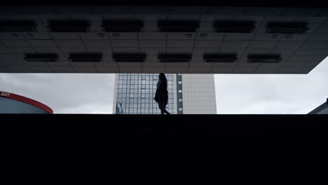 Silueta-Mujer-Caminando-Estacionamiento-Edificio-Oscuro-En-La-Ciudad-Al-Aire-Libre.