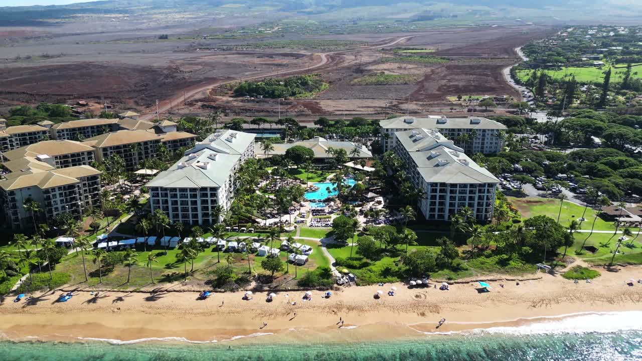 Forward drone move tilts up from lush resort shoreline to brown, fire-scarred hills