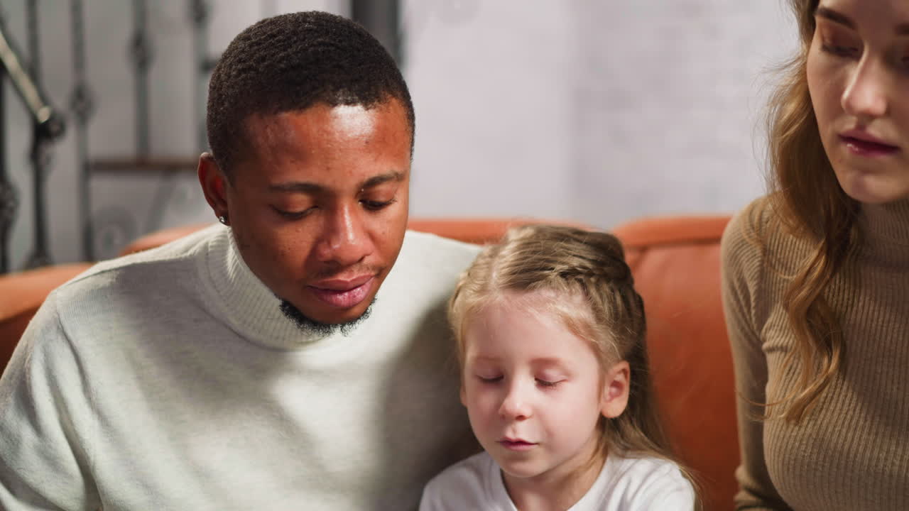 Woman with photobook and girl shows picture to guest at home