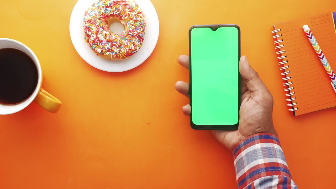 vista superior de la mano del hombre usando un teléfono inteligente sobre un fondo naranja