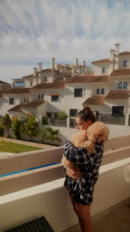 woman hugging a poodle on a balcony