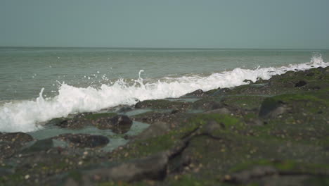 Medium-wave-hits-rocky-shore,-slow-motion