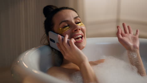 spa girl laying foam laughing mobile phone home. woman enjoying beauty routine