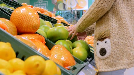 woman buying fresh exotic citrus fruits at grocery store