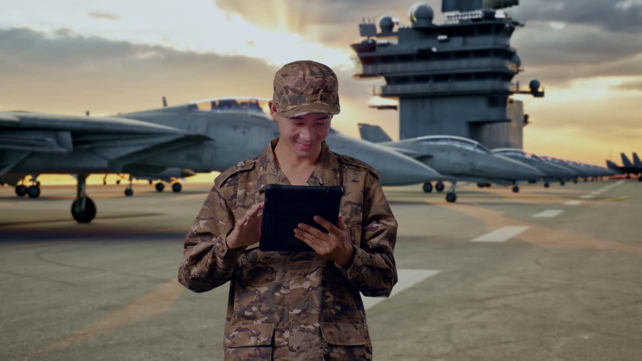 Military personnel using tablet on an aircraft carrier deck at sunset