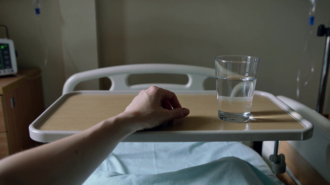Attempting patient left forearm making small reaching motions on overbed tray seeking glass in gown