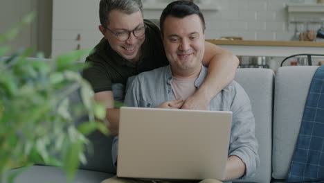 happy gay couple using laptop at home