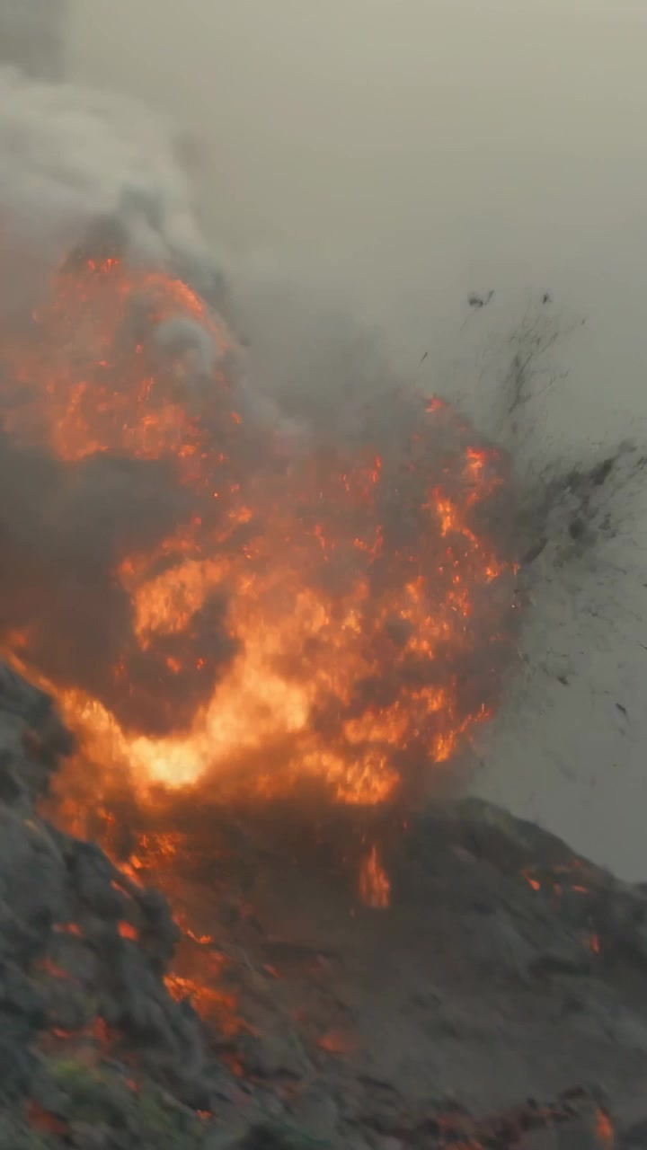 Video verticale: Sacche di magma fuso che alimentano un fronte eruttivo in movimento su un pendio roccioso, lanciando cenere e tefra