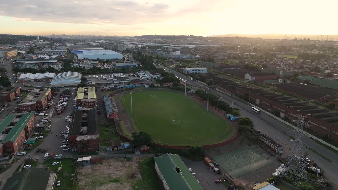 Drone clip of an empty soccer field with seating area built next to a road within an urban area