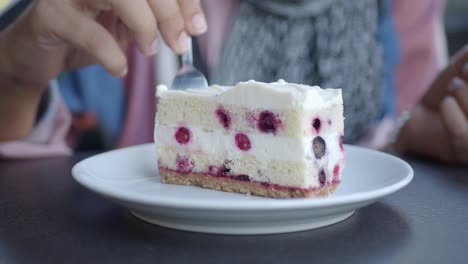 close up of a woman eating a slice of blueberry cake