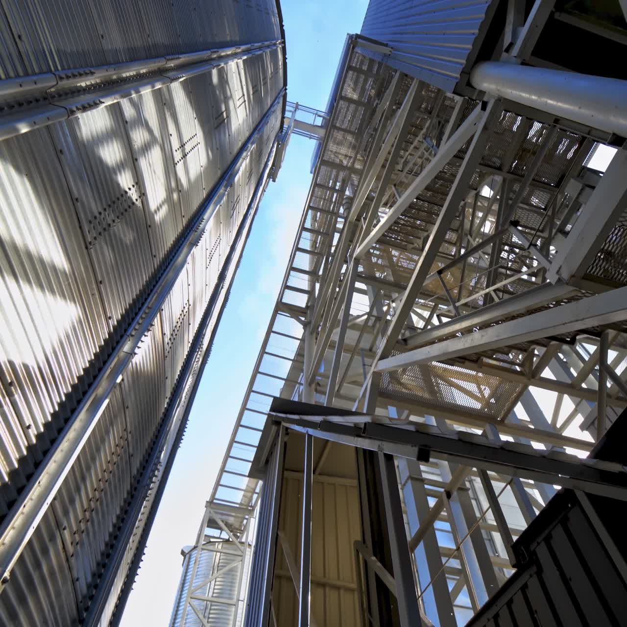Industrial equipment outdoors. Large metal terminals. Silver grain elevators on a modern plant for storing agricultural products. Close-up.