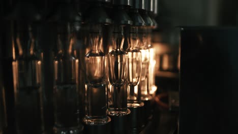 a series of glass bottles are being filled with liquid in a bottling factory